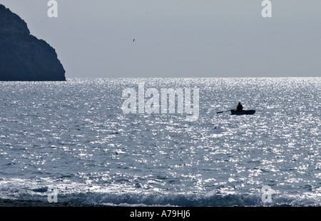 Andando a pesca: in una scintillante mare un pescatore in un piccolo canotto gode del sole del Mediterraneo Foto Stock