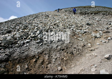 Pendio scivoloso: una donna con un bastone da passeggio opere il suo modo di discesa lungo il ripido sentiero silicea attraverso il ghiaione dalla santa montagna Foto Stock