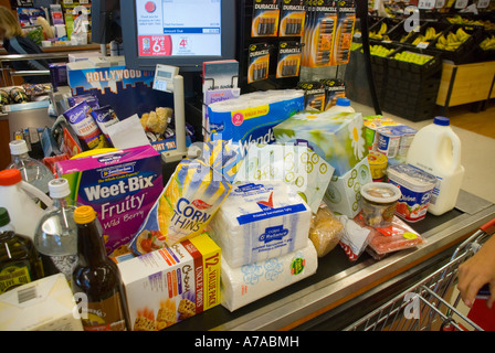 Lo shopping settimanale di una famiglia si accumulava al check-out del supermercato Foto Stock