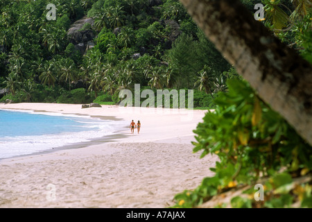 Giovane camminando lungo Anse Intendance shore sull'Isola di Mahe in Seychelles Foto Stock