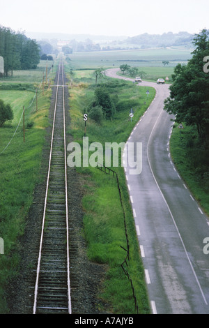 Strada di campagna e i binari della ferrovia che corre parallela attraverso la Francia rurale Foto Stock