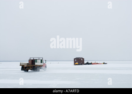 Puzzava di pesca attraverso il ghiaccio su un freddo giorno d'inverno sul Miramichi Bay New Brunswick Foto Stock