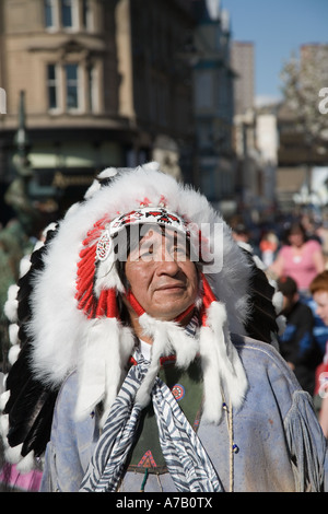 Musicista messicano indiano con la tradizionale headdress etnico piume. Animatore musicale di strada; Dundee City Center, Tayside, Scozia UK Foto Stock