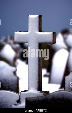 Neve su una croce in un cimitero Foto Stock