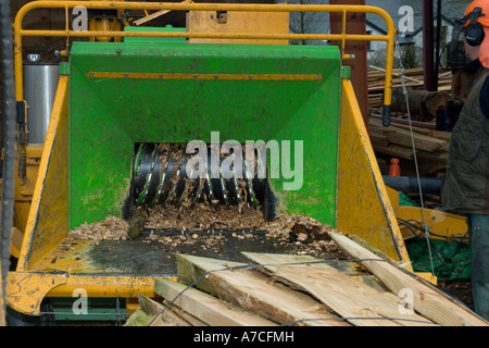 Truciolo essendo preparato da rifiuti slabwood per caldaie per il riscaldamento centrale con un trattore alimentato chipping macchina, Galles. Foto Stock