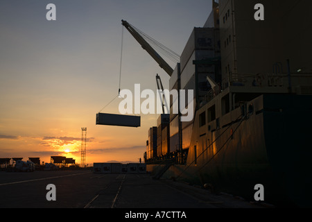 Lo scarico di contenitori di spedizione al tramonto dalla nave cargo profilarsi nel Porto di Caldera Costa Rica Repubblica America Centrale Foto Stock