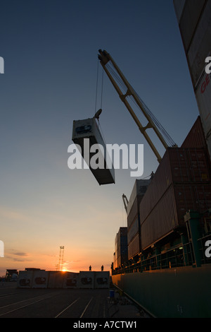 Lo scarico di contenitori di spedizione al tramonto dalla nave cargo profilarsi nel Porto di Caldera Costa Rica Repubblica America Centrale Foto Stock