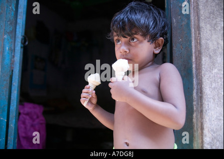 Un giovane ragazzo di mangiare due coni gelato a Dacca in Bangladesh Foto Stock