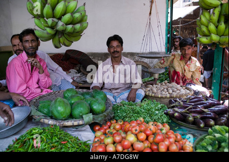 Gli uomini condividono un vegetale stallo a un mercato all'aperto a Dacca in Bangladesh Foto Stock