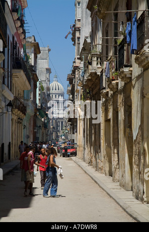 Un gruppo di uomini a piedi giù per una strada vicino a Plaza Vieja con Capitolio in background, l'Avana, Cuba. Foto Stock