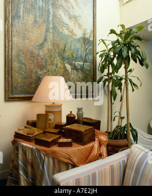 Collezione di antichi piccole scatole di legno sulla tavola circolare sotto la pittura di grandi dimensioni Foto Stock
