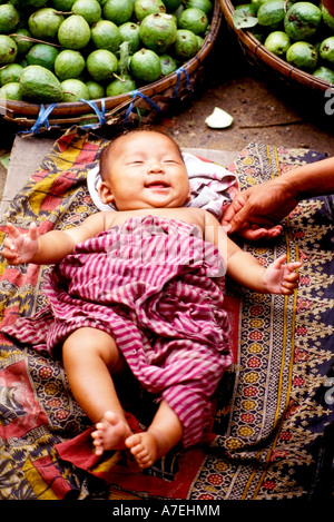 Sorridente bambino avvolto ina Khmer tradizionale sciarpa krama ad una strada del mercato di Phnom Penh Foto Stock