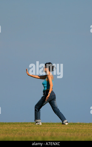 Una donna pratica l antica arte cinese del Tai Chi in un parco in una bella giornata Foto Stock