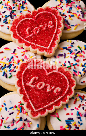 Due zucchero cotto cuore i cookie con la parola amore su di loro sulla sommità di glassa biscotti ricoperti con un pizzico Foto Stock