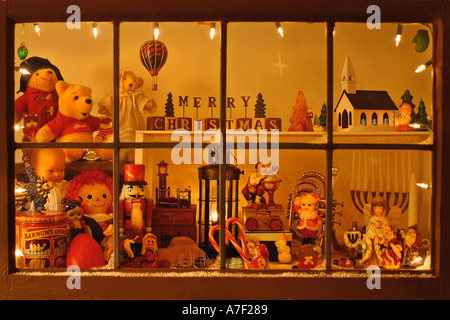Vetro piombato vetrina con la neve sul davanzale riempito di giocattoli di Natale e antichi ornamenti Foto Stock