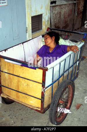 Donna che Dorme nel carrello al lato della strada e la città di Ho Chi Minh, Vietnam Foto Stock