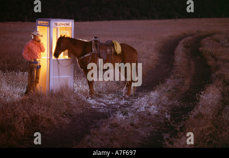 Cowboy effettua una chiamata telefonica in zona rurale remota Foto Stock