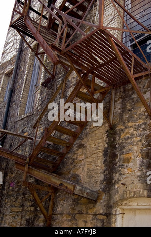 Il vecchio metallo arrugginito fire escape scalinata sul lato della costruzione di mattoni Foto Stock