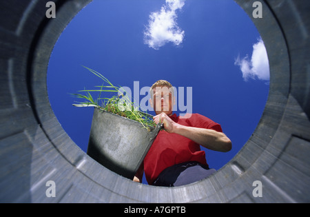 L'uomo gettando giardino dei rifiuti nel contenitore di riciclaggio per il compostaggio regno unito Foto Stock
