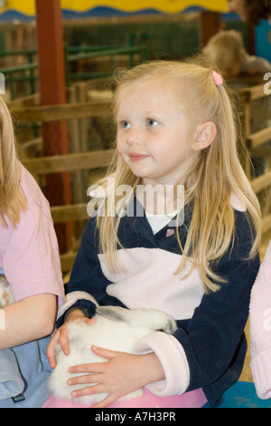 Ragazza giovane azienda lop eared rabbit razza rara fiducia Cotswold Farm Park Tempio Guiting vicino a Stow on the Wold Regno Unito Foto Stock