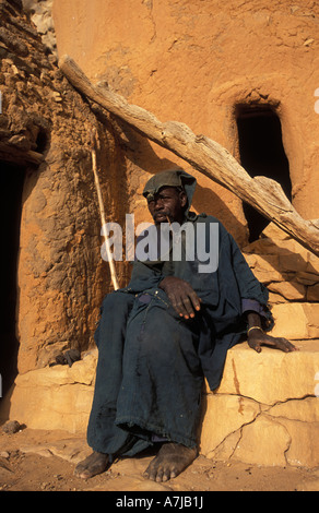 Hogon, leader spirituale di fumare un tubo nella sua scogliera scolpita home, Ende village, Paese Dogon del Mali Foto Stock