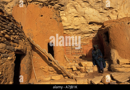 Hogon, leader spirituale di fumare un tubo nella sua scogliera scolpita home, Ende village, Paese Dogon del Mali Foto Stock