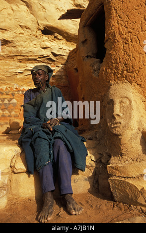 Hogon, leader spirituale di fumare un tubo nella sua scogliera scolpita home, Ende village, Paese Dogon del Mali Foto Stock