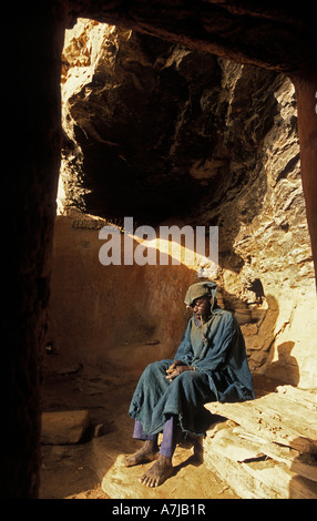 Hogon, leader spirituale di fumare un tubo nella sua scogliera scolpita home, Ende village, Paese Dogon del Mali Foto Stock