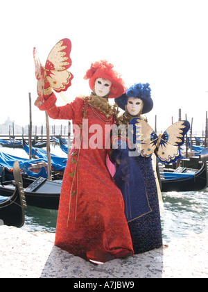 Due donne in rosso e blu costumi su quayside il carnevale di Venezia Foto Stock