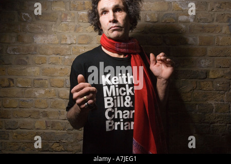 Un uomo di mezza età in maglietta dei rolling stones contro un muro di mattoni, con un espressione sognante, keith richard doppio Foto Stock