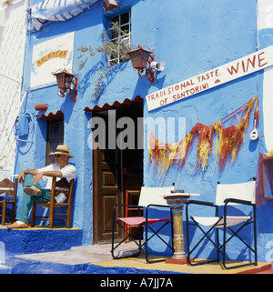 Uomo locale relax su una vecchia sedia in legno di prima mattina di sole in Street bar in Fira Santorini Isola Greco è la Grecia Foto Stock