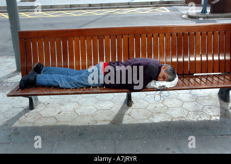 L'uomo addormentato sul sedile pubblico a Barcellona, in Catalogna, Spagna Foto Stock