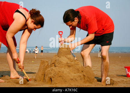 I giovani adulti divertirsi facendo un castello di sabbia. Foto Stock