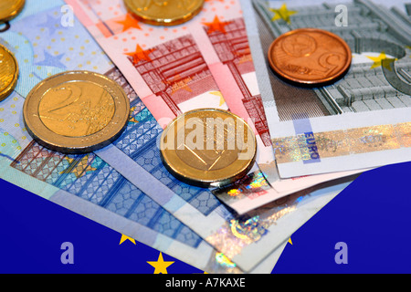 Denaro Euro contro un Euro bandiera dello sfondo. Foto Stock