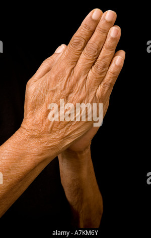 Una vecchia donna asiatica mantiene le sue mani nella preghiera Foto Stock