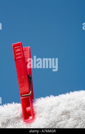 Vestiti pin su un asciugamano bianco e linea di lavaggio contro un cielo blu Foto Stock