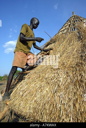 Etiopia - uomo copre il tetto di paglia di una casa Foto Stock