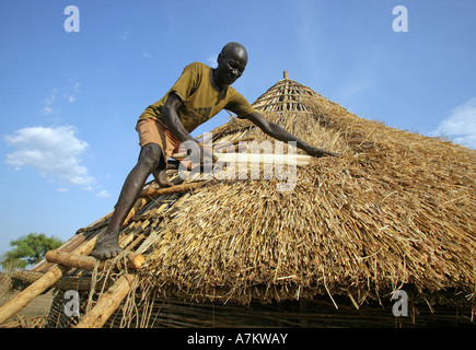 Etiopia - uomo copre il tetto di paglia di una casa Foto Stock