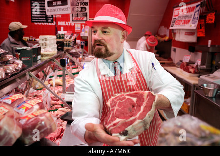 Un macellaio mostra un taglio di carne per un cliente nel suo negozio a Birmingham REGNO UNITO Foto Stock