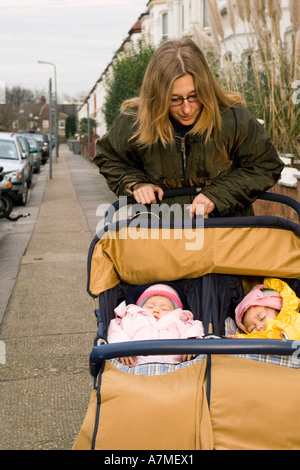 La madre con le ragazze in passeggino sulla Street, Londra, Inghilterra Foto Stock