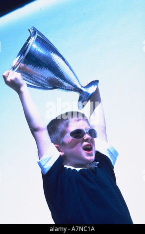 Ragazzo giovane azienda con orgoglio la coppa del trofeo Foto Stock