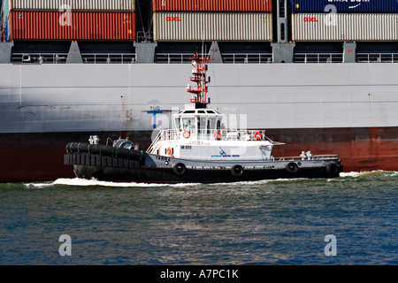 Industria di spedizione / una nave portacontainer è in entrata con un rimorchiatore a traino assistere.Porto di Melbourne in Australia. Foto Stock