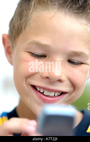 Close-up di ragazzo adolescente tramite telefono cellulare e sorridente Foto Stock