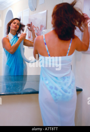 La riflessione di giovane donna asciugando i capelli in uno specchio Foto Stock