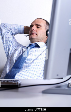 Imprenditore che indossa la cuffia e il riposo in ufficio Foto Stock