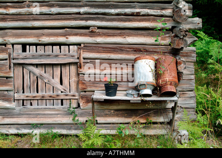 Bidoni per il latte nella parte anteriore del log cabin, Finlandia Foto Stock