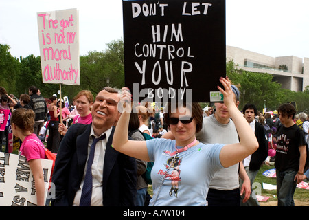 Una donna detiene il segno come essa si erge accanto a qualcuno che indossa George W Bush questa maschera è stata presso la scelta Pro Rally il 25 aprile 2003 Foto Stock