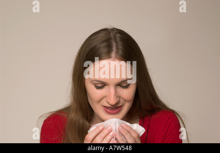 Donna caucasica che starnutisce in un tessuto, tenendo in mano un Kleenex durante un episodio di freddo o allergia, USA. Foto Stock