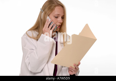 Donna caucasica medico generico sul telefono durante la revisione del file paziente in ufficio medico, Stati Uniti d'America. Foto Stock