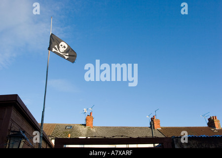 Jolly Roger pirati bandiera volare sopra i tetti a schiera Foto Stock